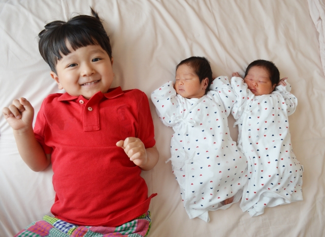 双子の赤ちゃんと上の子が横になっている写真